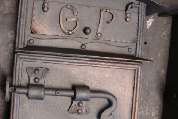 Kovaná poštovní schránka s logem.